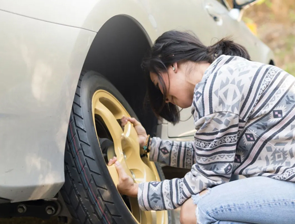 woman on side of the road changing a flat tire